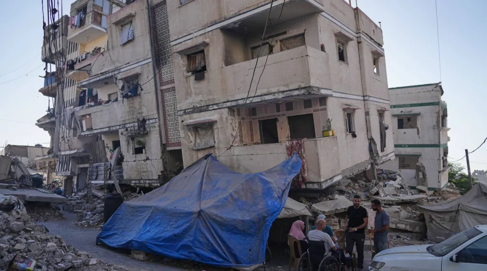 فلسطينيون اتخذوا ملجأ بجوار منزل متضرر من القصف الإسرائيلي على قطاع غزة (أ.ب)