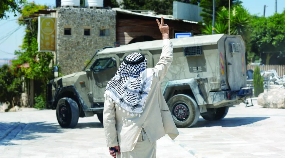 مستوطنون وجنود إسرائيليون يقفون بحقل في حين يُمنع المزارعون الفلسطينيون من قطف الزيتون بقرية سعير قرب مدينة الخليل بالضفة الغربية (أرشيفية - أ.ف.ب)