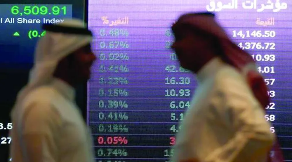 رجلان يتحدثان أمام إحدى شاشات الأسهم في السوق السعودية (رويترز)