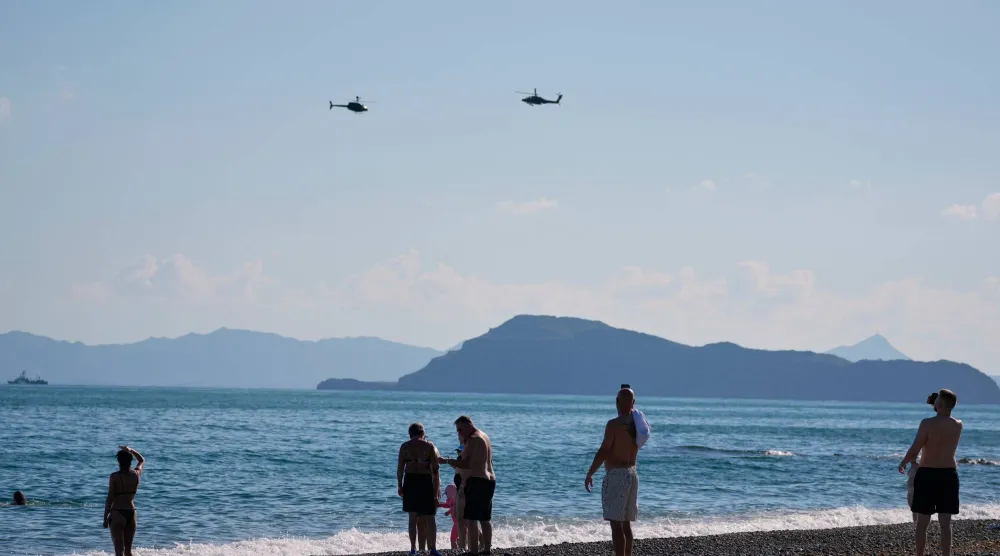 Tourists from a nearby hotel watch military helicopters fly overhead during Medusa 15, a joint military exercise led by Greece and Egypt, at Maleme on the Greek island of Crete, Friday, Sept. 18, 2026. (AP Photo/Thanassis Stavrakis)