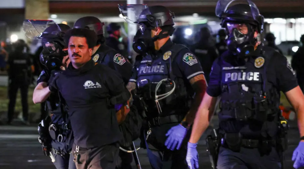 Polis ekipleri, Austin'de bir kişinin ABD Göçmenlik ve Gümrük Muhafaza (ICE) ajanı tarafından vurularak yaralanmasının ardından düzenlenen protestolar sırasında bir adamı gözaltına alıyor. (Reuters)