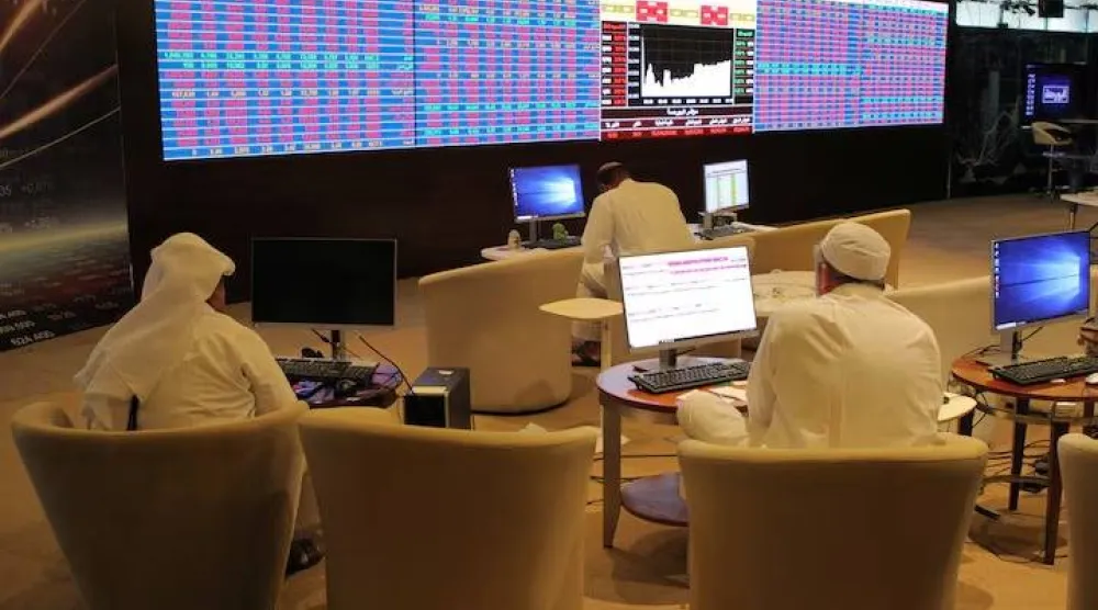 مستثمرون في قطر يتابعون أسعار الأسهم على شاشة التداول ببورصة الدوحة (رويترز)