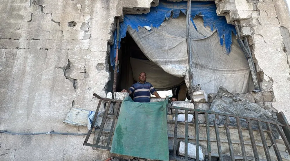 Palestinian Bassam Nusseir, a displaced person in Gaza City, stands amidst the rubble of a collapsed building housing him and his family (Asharq Al-Awsat)