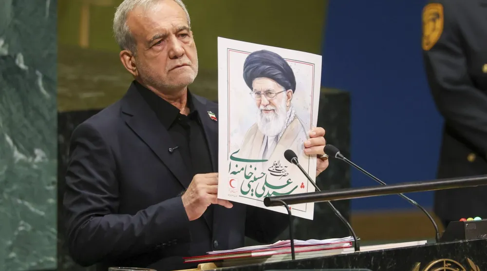 بزشكيان رافعاً صورة علي خامنئي في الأمم المتحدة (رويترز)