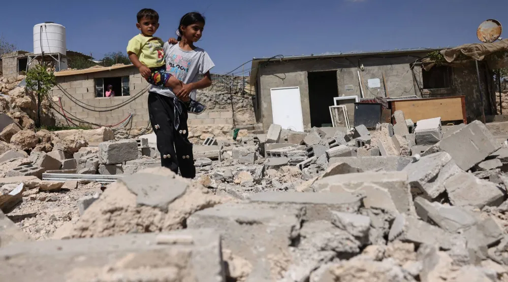 طفلان فلسطينيان يقفان وسط أنقاض منزل هدمته القوات الإسرائيلية في قرية «جنبا» بالضفة الغربية المحتلة الأربعاء (أ.ف.ب)