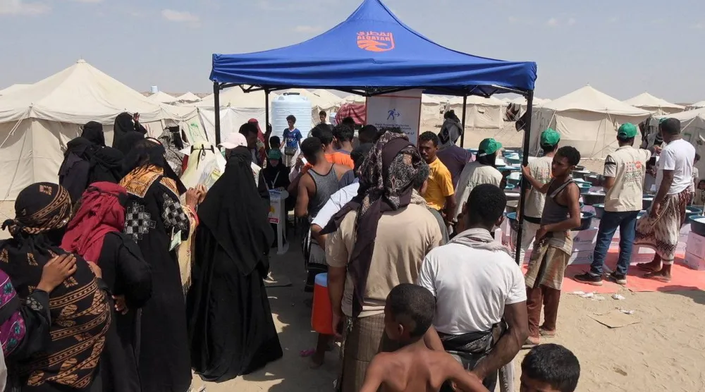 يمنيون فارون من القتال يقفون في طابور للحصول على قسائم غذائية قرب عدن أمس (رويترز)