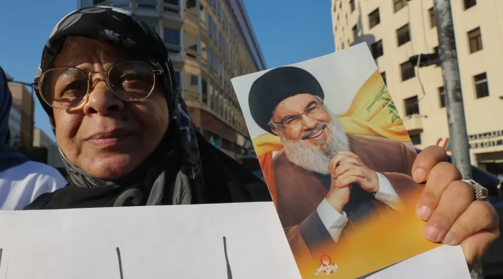 Hizbullah destekçisi bir kadın, ABD arabuluculuğunda yürütülen Lübnan-İsrail müzakerelerine karşı Beyrut merkezindeki protestolar sırasında, örgütün eski Genel Sekreteri Hasan Nasrallah’ın fotoğrafını taşıyor (Arşiv- EPA)