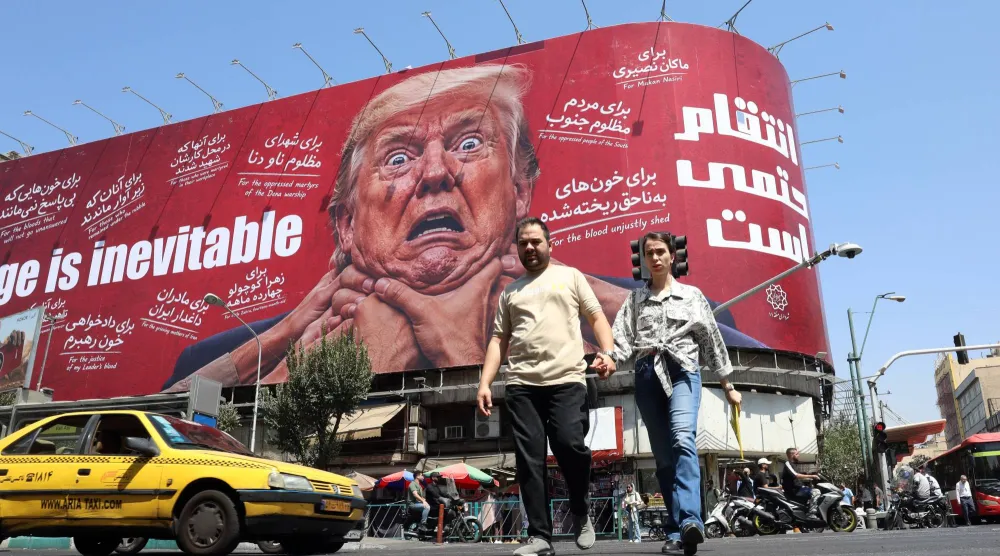 إيرانيون يمرون قرب لوحة مناهضة للرئيس الأميركي دونالد ترمب في طهران (إ.ب.أ)