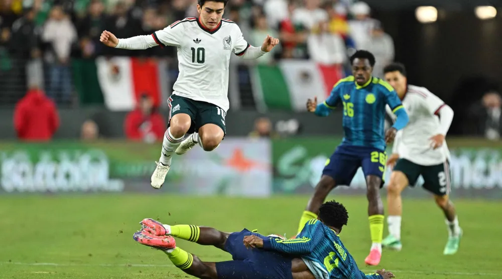 غيلبرتو مورا لاعب المكسيك يقفز فوق الكولومبي ألفارو أنغولو لتفادي تدخُّل خلال المباراة الودية بين المنتخبين في بالتيمور (أ.ف.ب)