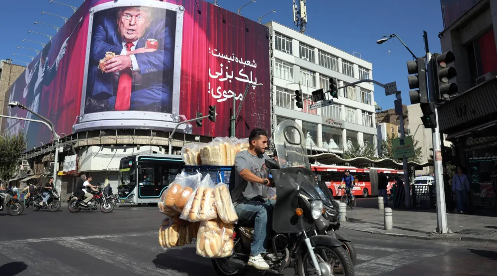  إيراني يقود دراجته النارية أمام لوحة دعائية مناهضة للرئيس الأميركي دونالد ترمب في طهران الأسبوع الماضي (إ.ب.أ)