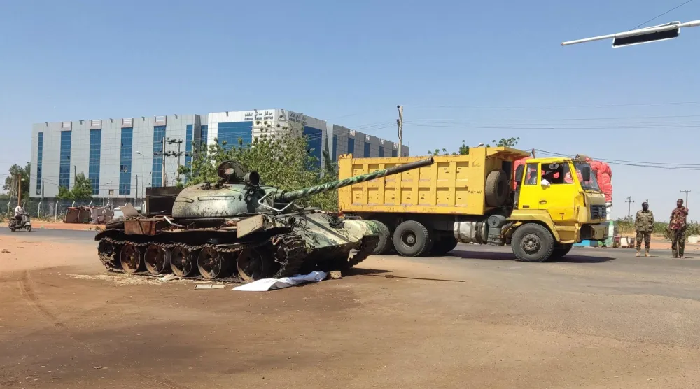 شاحنة تمر بجوار دبابة في مدخل ود مدني بالسودان خلال فبراير 2025 (أ.ف.ب)