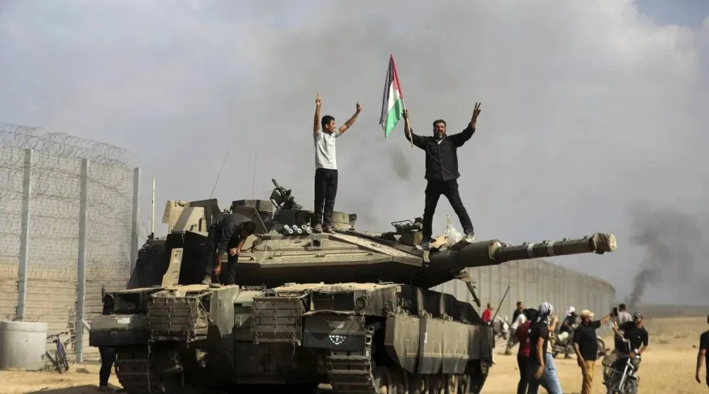 فلسطينيون يحتفلون على ظهر دبابة إسرائيلية على الجدار العازل قرب خان يونس في جنوب قطاع غزة يوم 7 أكتوبر 2023 (أ.ب)