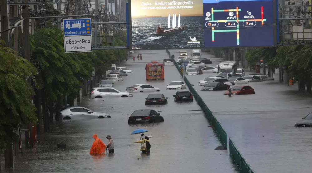 People wade through floodwater as submerged vehicles remain abandoned along Phetchaburi Road in Bangkok, Thailand, 26 September 2026. EPA/RUNGROJ YONGRIT
