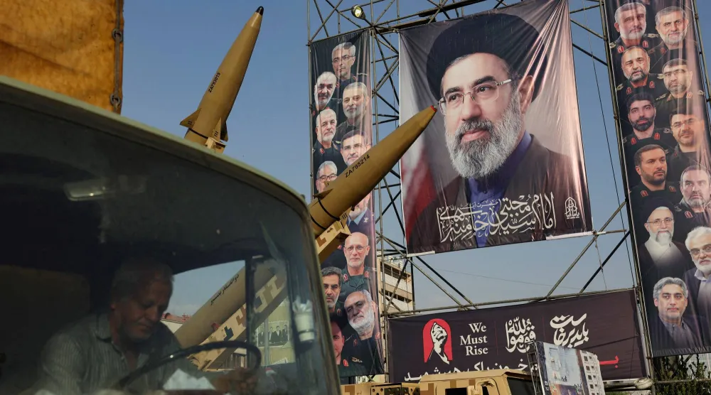 صواريخ إيرانية معروضة بجوار لوحة تحمل صورة المرشد مجتبى خامنئي في أحد شوارع طهران، الأحد (رويترز)
