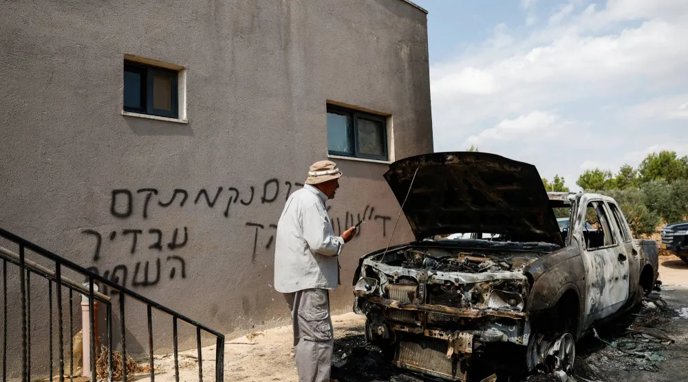 فلسطيني يفحص آثار الدمار يوم الاثنين بعد هجوم لمستوطنين إسرائيليين على قرية قرب رام الله في الضفة الغربية المحتلة (رويترز)