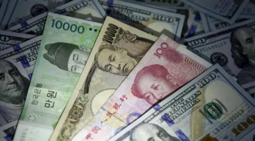 أوراق نقدية من الوون الكوري الجنوبي واليوان الصيني والين الياباني على أوراق نقدية من فئة 100 دولار أميركي (رويترز)