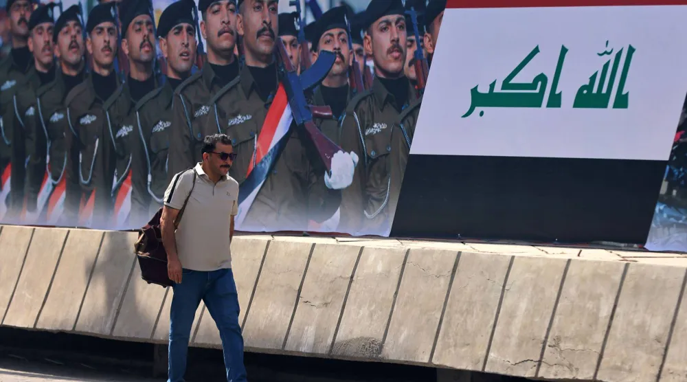 عراقي يسير بمحاذاة إعلان مثبت على جانب شارع في بغداد يوم 29 سبتمبر 2026 تزامناً مع نهاية مهمة التحالف الدولي ضد «داعش» (أ.ف.ب)