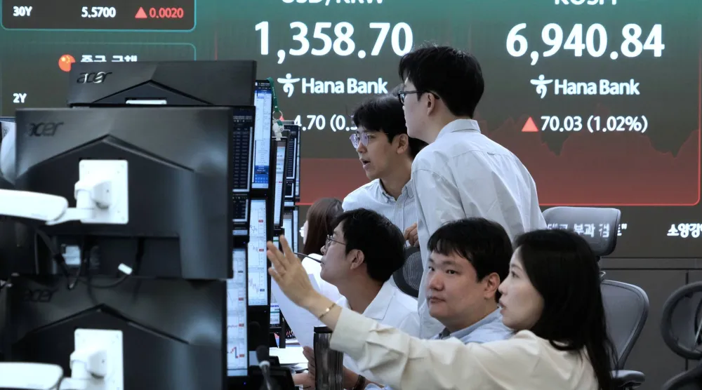 متداولون يعملون بالقرب من شاشة تعرض مؤشر «كوسبي» وسعر صرف العملات الأجنبية بين الدولار الأميركي والوون في غرفة تداول العملات الأجنبية بمقر بنك هانا في سيول (أ.ب)