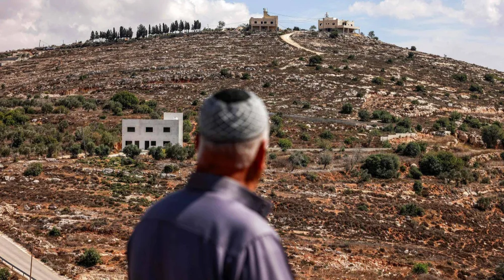 محمود الطوباسي فلسطيني يبلغ من العمر 60 عاماً كان قد هُجِّر من منزله قبل أشهر إثر هجوم شنه مستوطنون إسرائيليون حيث يقف ناظراً من مسافة بعيدة إلى منزله في قرية جالود الفلسطينية الواقعة جنوب نابلس في الضفة الغربية التي تحتلها إسرائيل (أ.ف.ب)