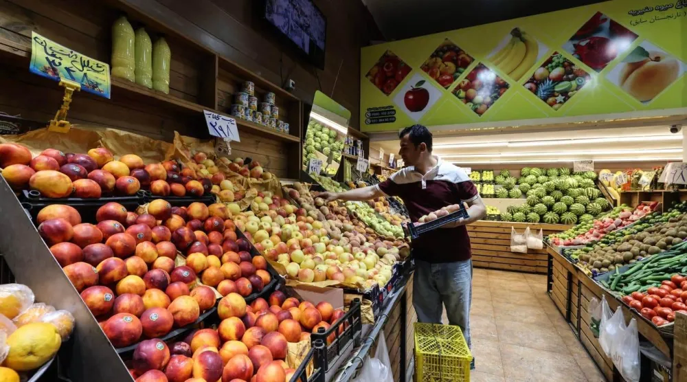 Tahran’ın güneyindeki bir marketteki bir adam meyveleri düzenliyor (AFP)