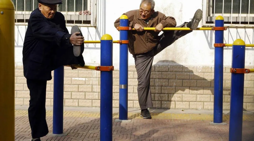 Pekin’deki bir parkta Çinli yaşlı erkekler esneme egzersizleri yapıyor (AFP)