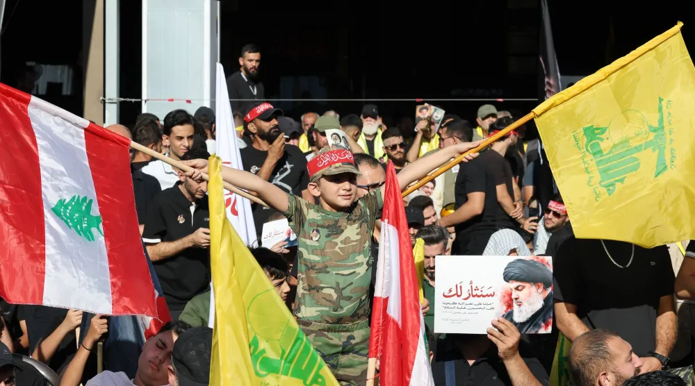 مناصرون لـ«حزب الله» يحملون العلم اللبناني وعلم الحزب خلال إحياء الذكرى الثانية لاغتيال أمينه العام السابق حسن نصر الله (إ.ب.أ)