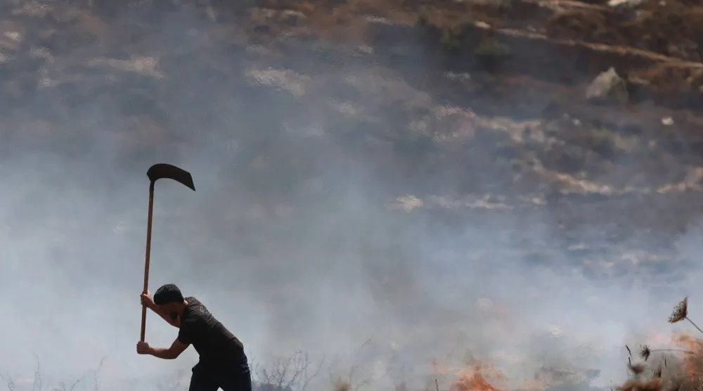 مزارع فلسطيني يحاول إخماد النيران في عصيرة القبلية جنوب نابلس بعد هجمات للجيش ومستوطنين (أ.ف.ب)