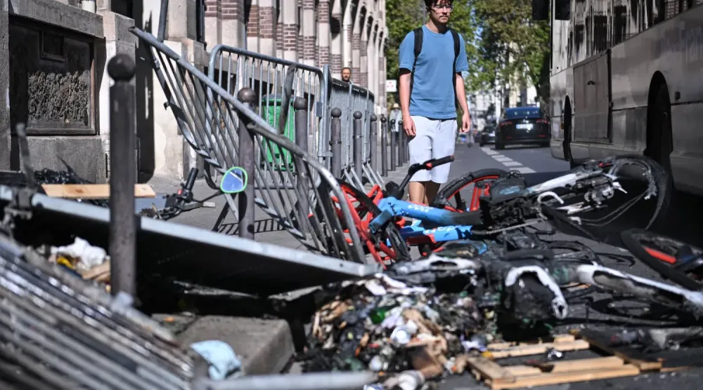 Paris’te lise öğrencilerinin düzenlediği protesto sırasında polis ile göstericiler arasında çıkan çatışmaların ardından bölgede meydana gelen yıkımın izleri önünden geçen bir kişi (EPA)