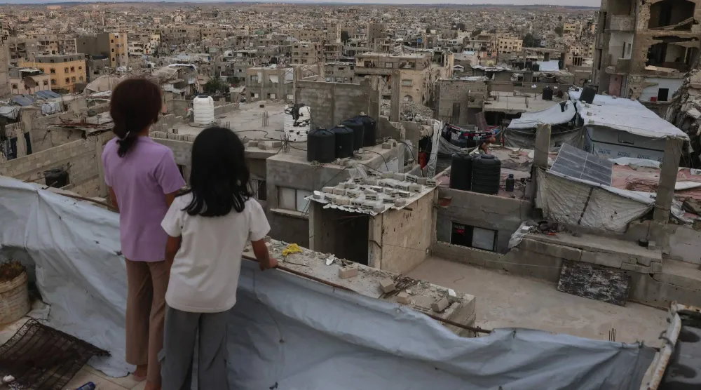 أطفال فلسطينيون يقفون أعلى سطح في مخيم جباليا شمال قطاع غزة أمس (أ.ف.ب)