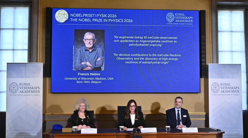 Eva Olsson, Ellen Moons, and Mark Pearce sit in front of a screen displaying Francis Halzen as the recipient of the 2026 Nobel Prize in Physics during a press conference at the Royal Swedish Academy of Sciences in Stockholm, Sweden, on October 6, 2026. (Photo by Christine OLSSON / TT NEWS AGENCY / AFP) 