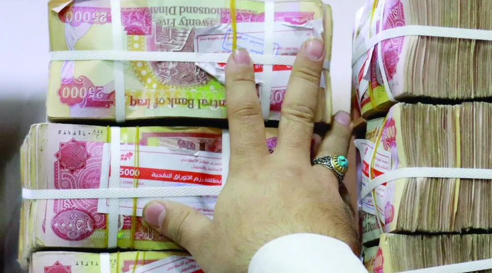 موظف يرتب أكواماً من الدينار العراقي في محل صرافة ببغداد (أ.ف.ب)