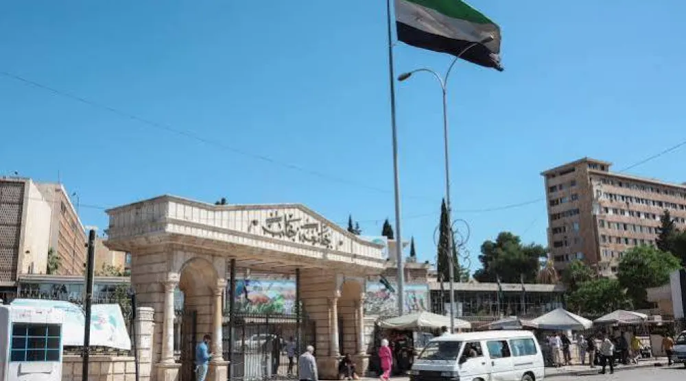 مارة قرب مدخل جامعة حلب والعلم السوري يوم 14 مايو 2025 (رويترز)