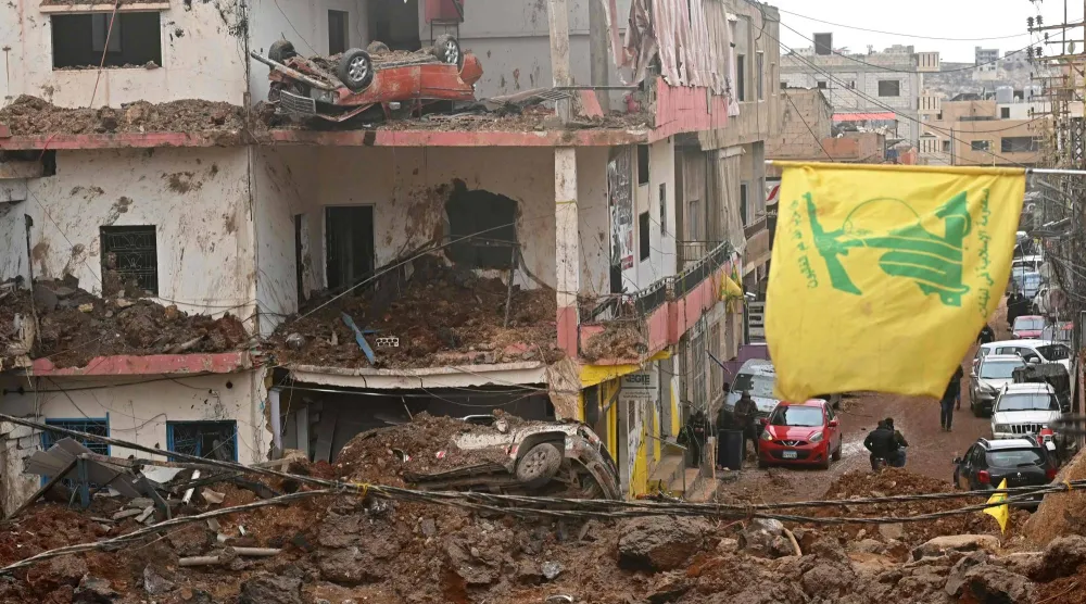 This photograph taken during a media tour organized by Hezbollah shows a flag of Hezbollah installed on the balcony of a damaged building at Nabi Sheet town after an Israeli military operation in the Bekaa Valley of Lebanon, on March 7, 2026. (Photo by FADEL itani / AFP)