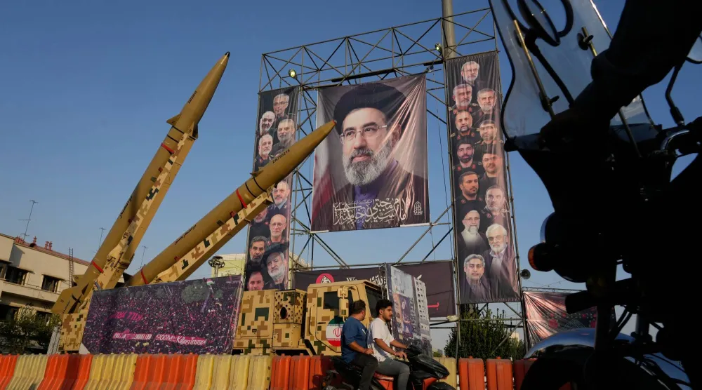 إيرانيون على دراجات نارية يمرون أمام صواريخ وصور للمرشد الإيراني مجتبى خامنئي وقادة عسكريين وعلماء نوويين قُتلوا في ضربات أميركية وإسرائيلية بطهران (أ.ب)