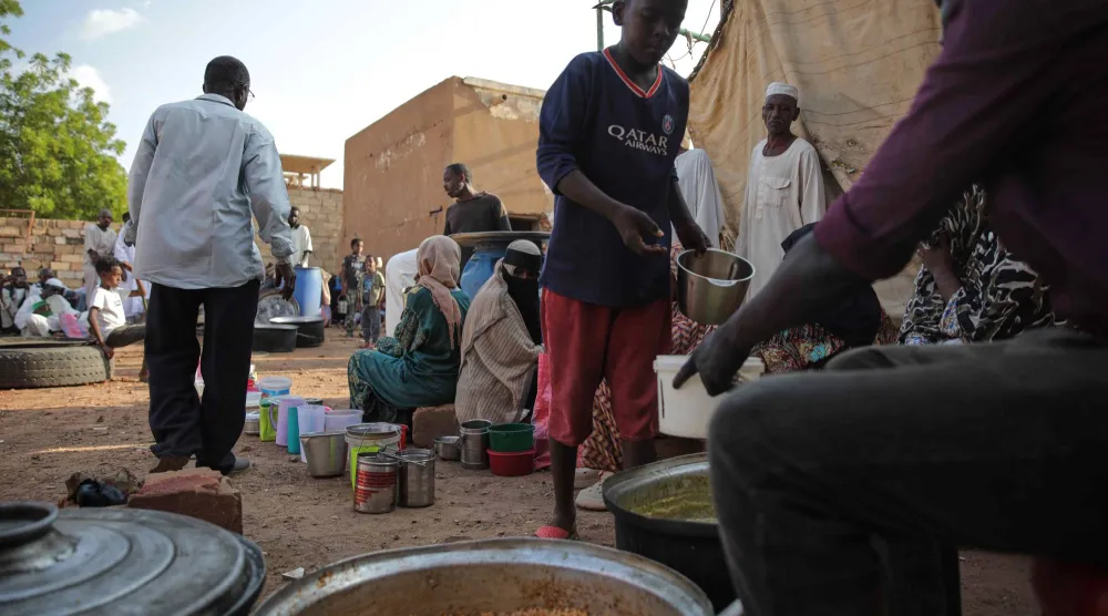 فتى سوداني يمسك وعاء للحصول على طعام من مطبخ خيري بالخرطوم 23 سبتمبر الماضي (أ.ب)