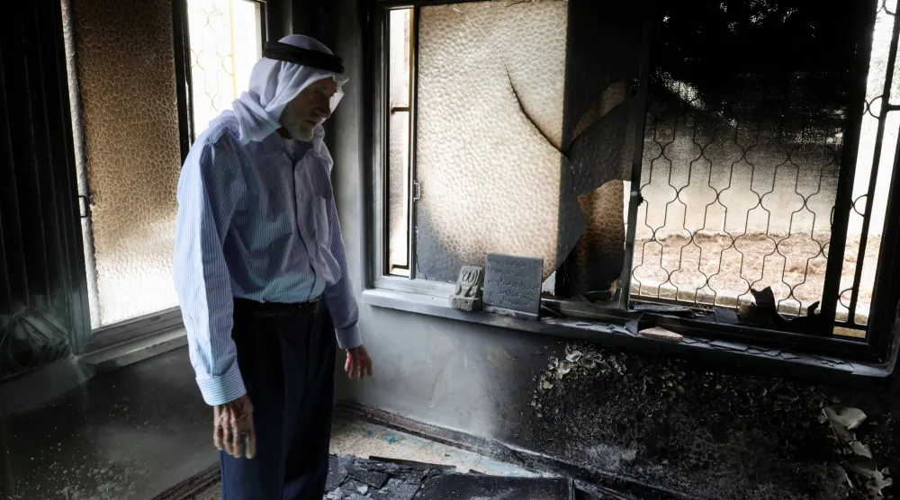 فلسطيني يتفقد الأضرار في مسجد أحرقه مستوطنون إسرائيليون في قرية مخماس قرب رام الله بالضفة الغربية الأربعاء (رويترز)