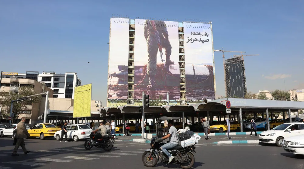 إيرانيون يمرون بسياراتهم أمام لوحة إعلانية مناهضة للولايات المتحدة في ساحة «فاناك» بطهران يوم 14 أكتوبر 2026 (إ.ب.أ)