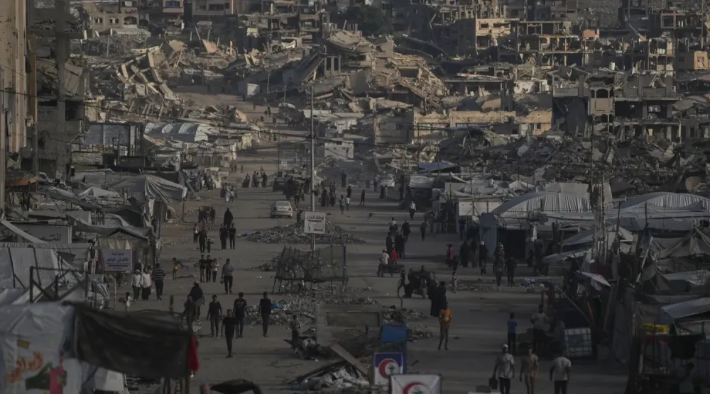 Gazze şehrinde yıkılmış binaların arasında yürüyen Filistinliler (AP)
