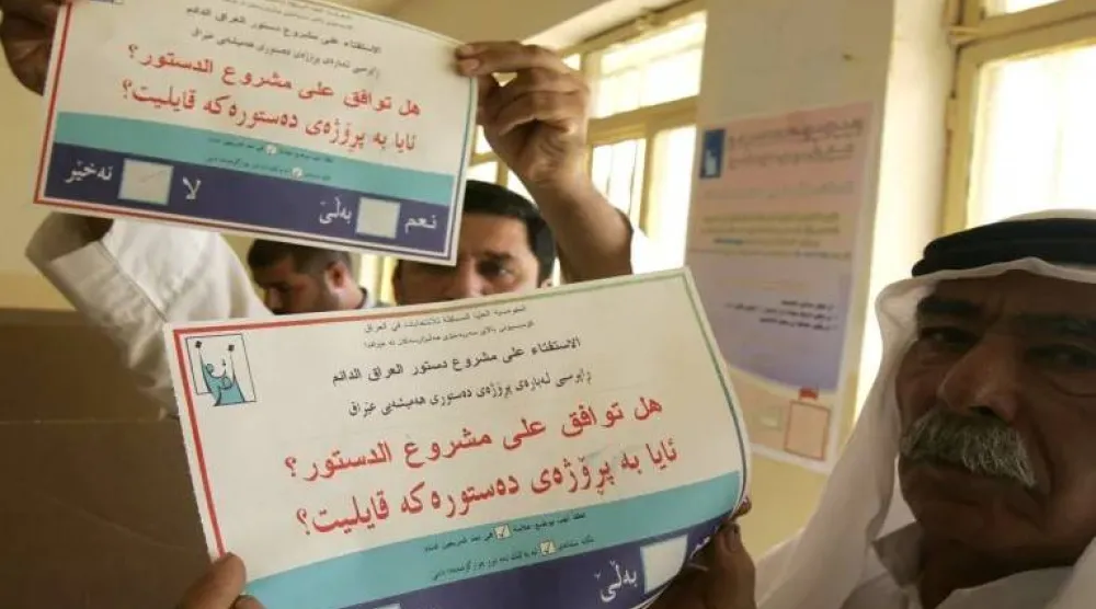 عراقيان يلوّحان بورقة الاستفتاء على الدستور الدائم في 15 أكتوبر 2005 (أ.ف.ب)
