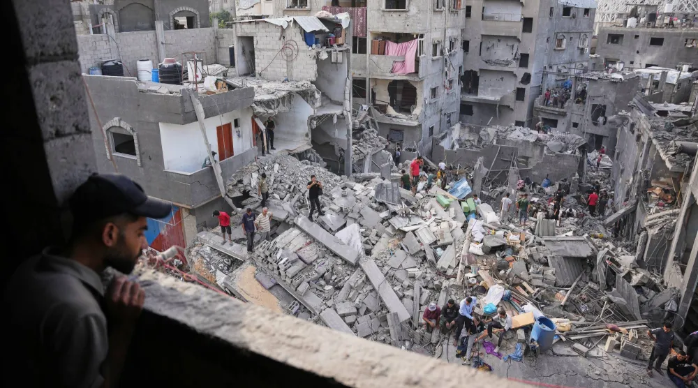 فلسطينيون يبحثون عن ناجين تحت أنقاض بناية دمرها القصف الإسرائيلي ليلاً في «مخيم المغازي» (أ.ب)