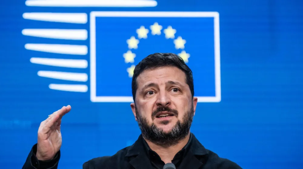 الرئيس الأوكراني فولوديمير زيلينسكي وخلفه شعار الاتحاد الأوروبي على هامش قمة لزعماء التكتل (د.ب.أ)