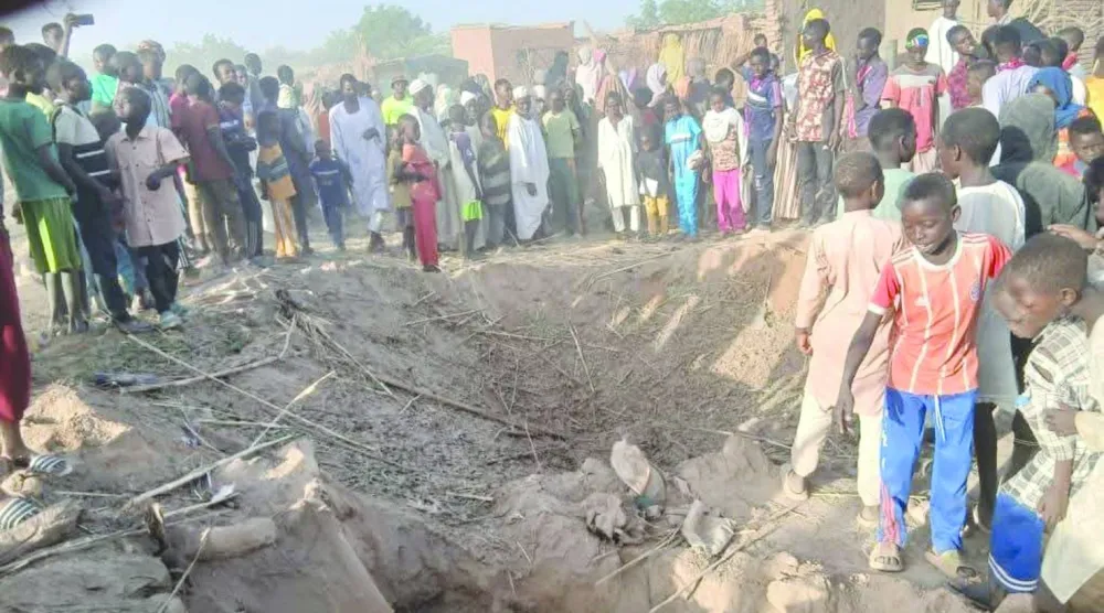 سودانيون يعاينون حفرة سببتها مُسيَّرة استهدفت في وقت سابق مخيماً للنازحين بوسط دارفور (الأمم المتحدة)