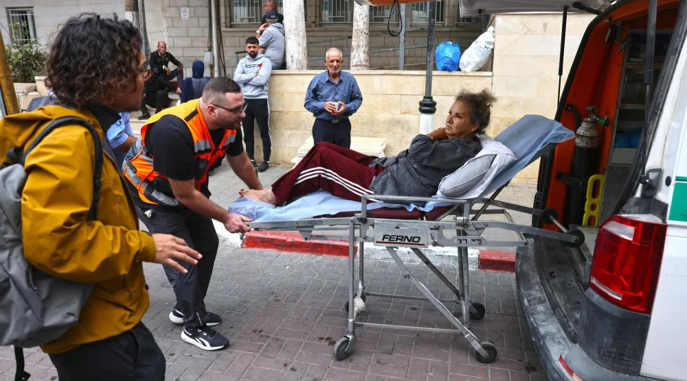 نقل المصورة الصحافية الأميركية هايدي ليفين إلى سيارة إسعاف فلسطينية بعد الاعتداء عليها في الضفة الغربية (أ.ف.ب)