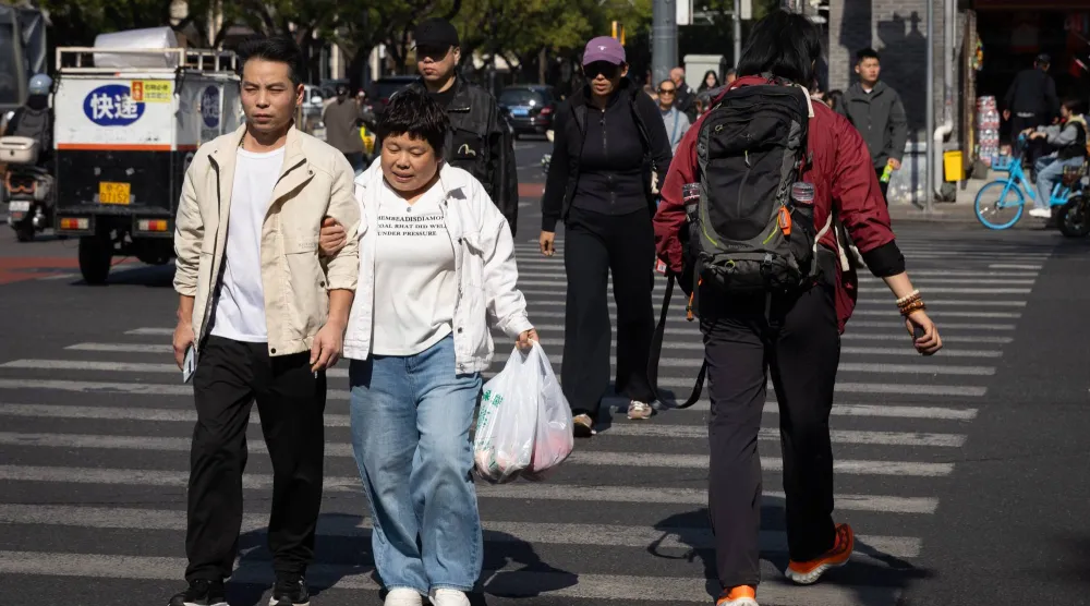 People cross the street at a busy intersection in Beijing, China, 19 October 2026. (EPA)
