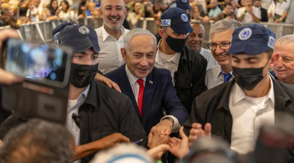 Israeli Prime Minister Benjamin Netanyahu stands amid security personnel as he meets with voters at a mall in Ramle on October 19, 2026. (AFP)