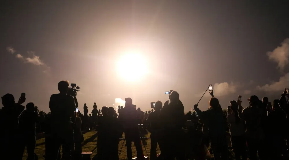 People watch the launch of the H3 rocket, carrying the Martian Moons eXploration (MMX) spacecraft, at the Tanegashima Space Center in Kagoshima Prefecture on October 20, 2026. (Photo by JIJI Press / AFP)