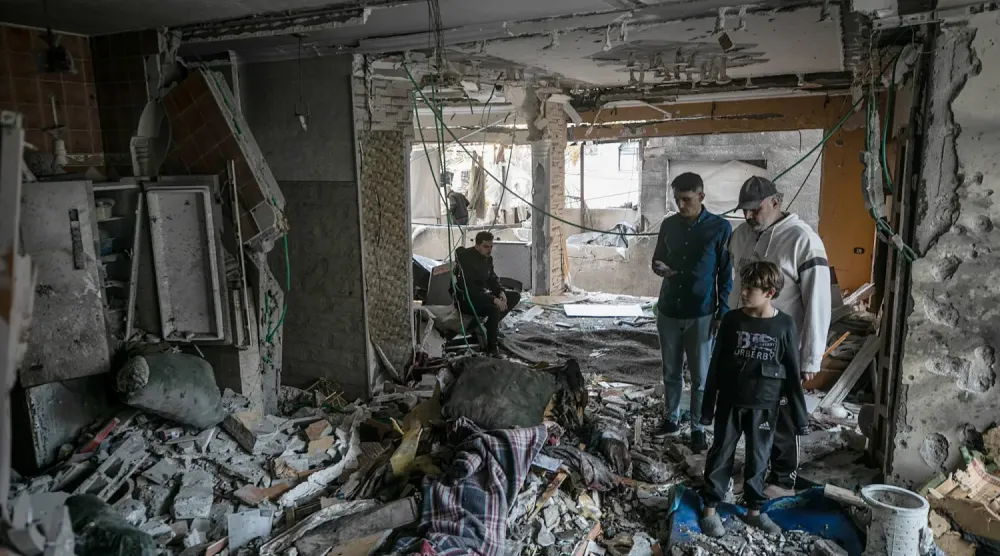Filistinliler, 20 Ekim 2026'da Gazze kentinin batısında düzenlenen İsrail hava saldırısında yıkılan bir evi inceliyor. (AP)