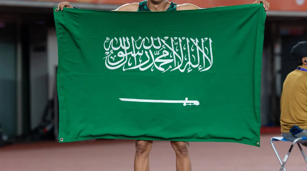السعودي ثامر الزهراني حاملاً علم بلاده ومحتفلاً بالإنجاز (فريق السعودية)