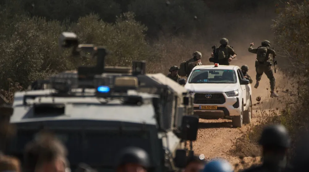 قوات إسرائيلية تصل إلى طريق مغلق يمنع الفلسطينيين من الوصول إلى بساتينهم لقطف الزيتون في بلدة ترمسعيا بالضفة الغربية يوم الأربعاء (أ.ب)