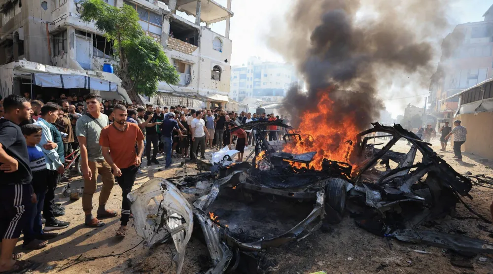 فلسطينيون يتجمَّعون حول مركبة مشتعلة بعد تعرُّضها لضربة إسرائيلية وفقاً لمسؤولين بالقطاع الصحي في مدينة غزة (رويترز)